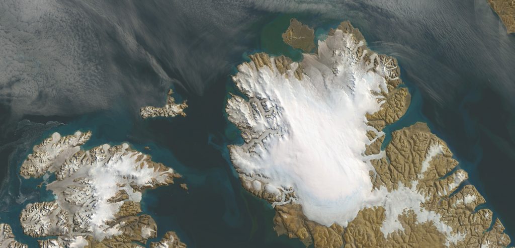 Jay Hart&nbsp;• <em>Devon Icecap</em>&nbsp;• Inkjet print of Landsat imagery&nbsp;• 49″×&nbsp;24″&nbsp;• $600.00<div class="fb-text&quot><p style="margin-top:5px; text-align:center; font-size: 0.8em; ">This complex area includes nearshore fog-bank climates and the always windy and frozen crests. Like the Barnes it is giving way to warming fastest on its south (right) sides: outlet glaciers bulge with blended rocky content, and even are pushed to the threshold of making smaller, less cohesive outlets, as if a warm week or month had triggered something different. There is much to learn and little time to mull it over. The icecap is well known (radar has measured its layers), and while it may survive for some time, it soon will be a beanie of its former self. Its importance lies in what it can teach us now, in the throes of its disappearance. We'd be better off to know its lessons.</p></div>