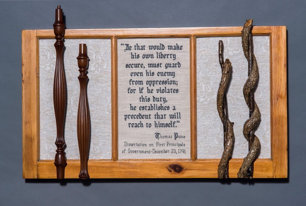 Eva M. Capobianco&nbsp;• <em>Guard Even Your Enemy</em>&nbsp;• Cross stitch, linen & found wood&nbsp;• 34″×&nbsp;22″×&nbsp;3″&nbsp;• $475.00