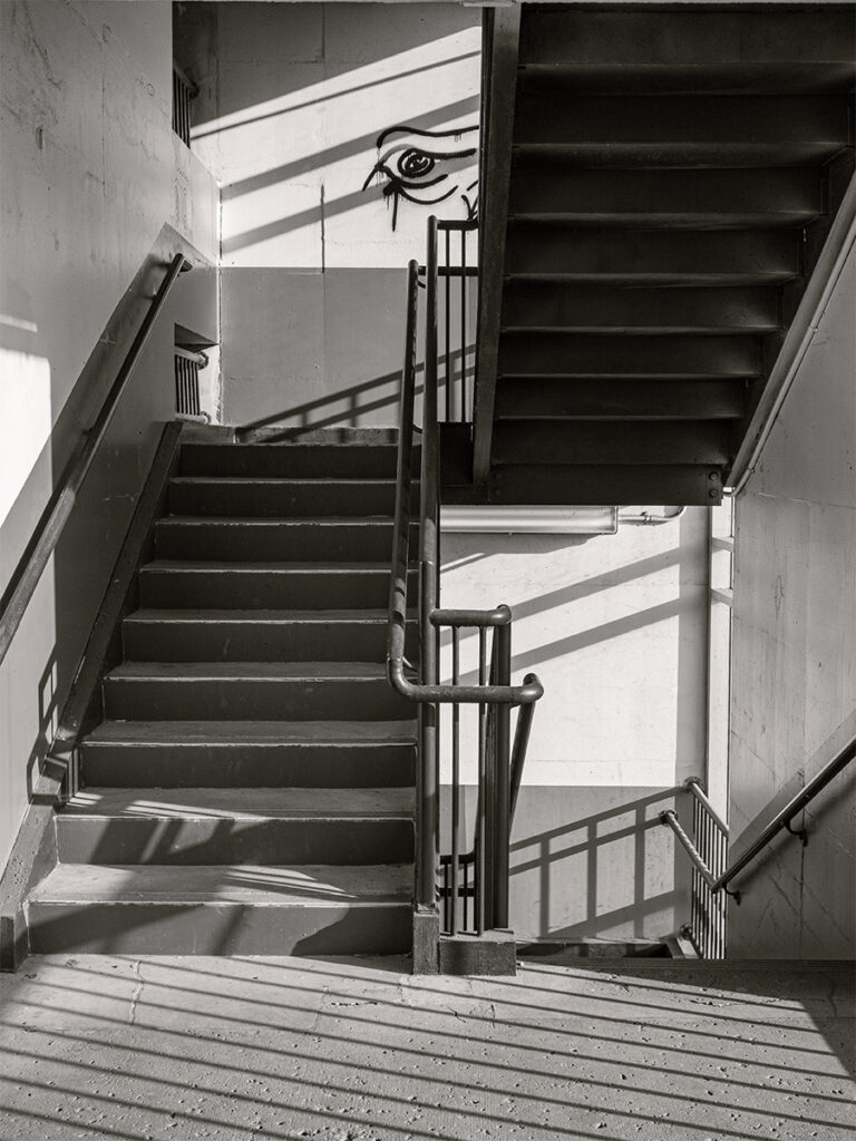 Laurie Schutt&nbsp;• <em>The stairwell is watching</em>&nbsp;• Print on metal&nbsp;• 12″×&nbsp;18″&nbsp;• $180.00